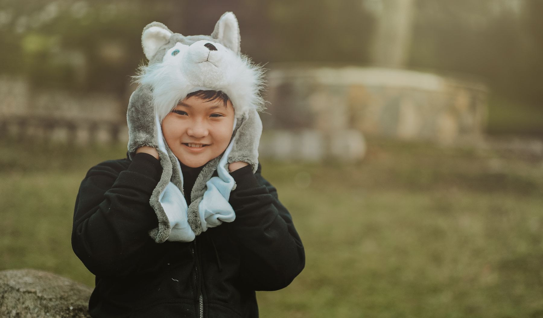 Smiling child in a gray and white knit cap outdoors