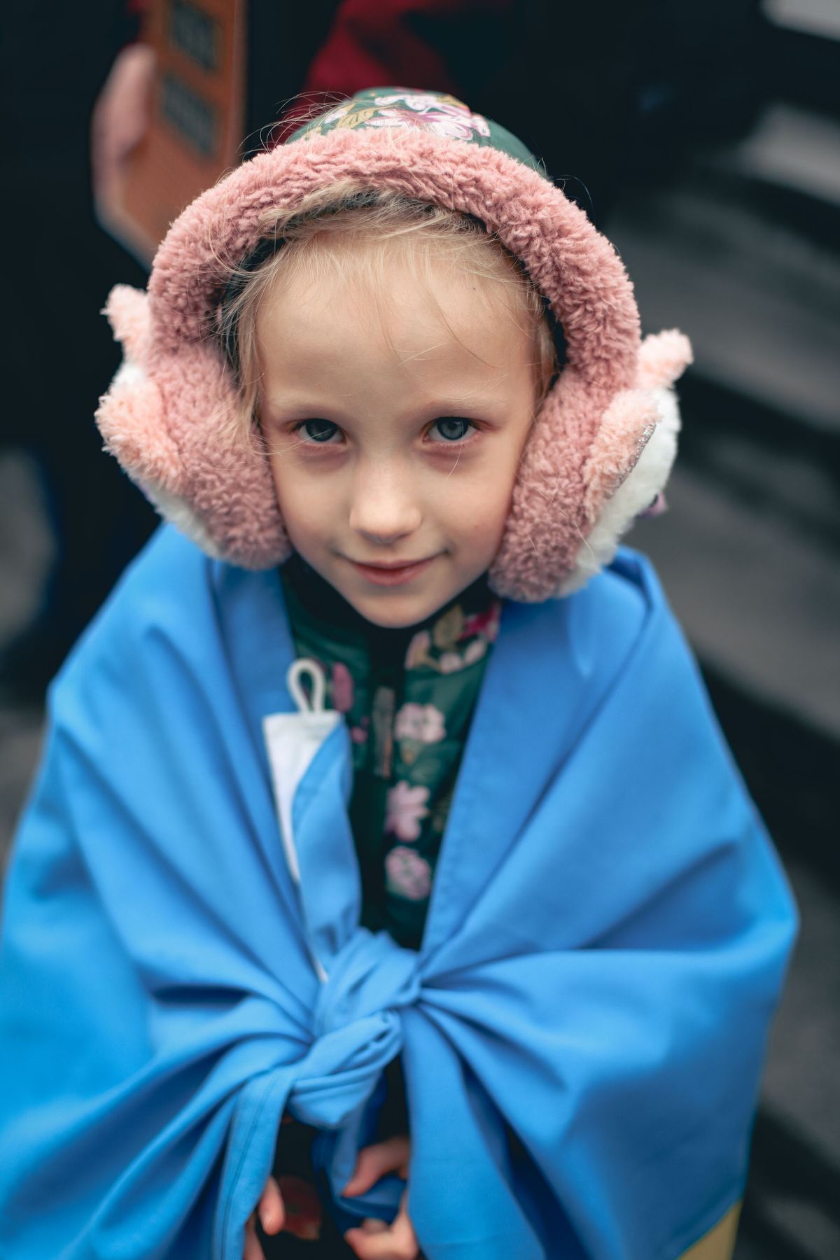 Girl wearing pink ear muffs and a blue shawl