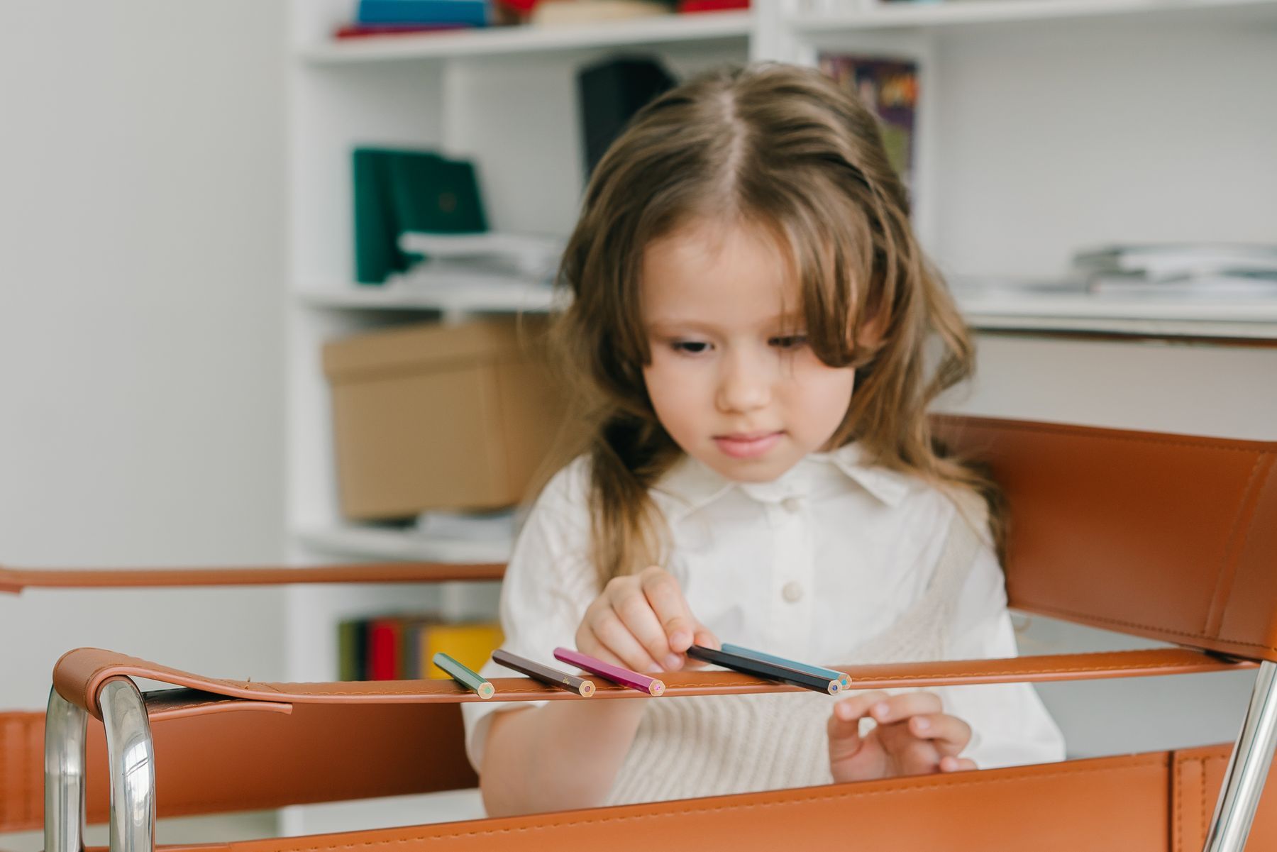 Young girl choosing colored pencils at a desk