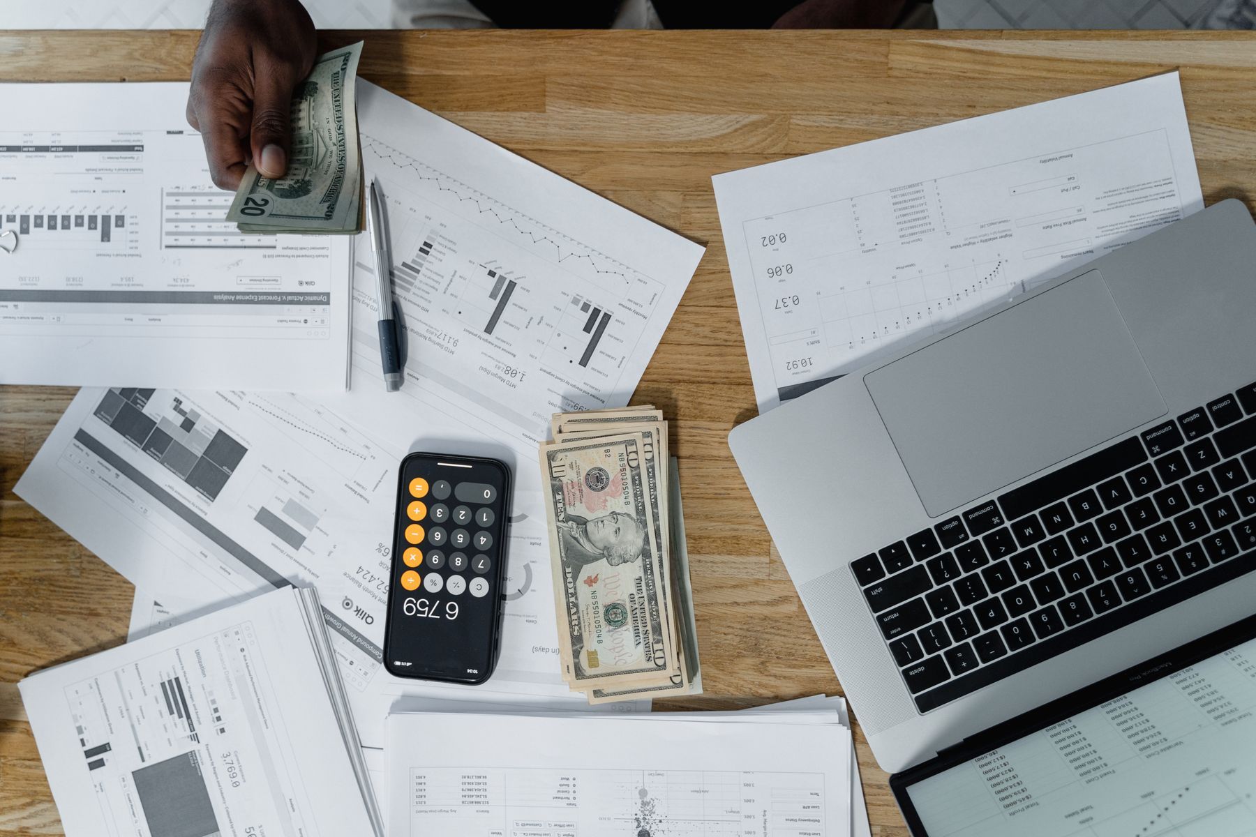 Desk with paperwork, a calculator, and a laptop
