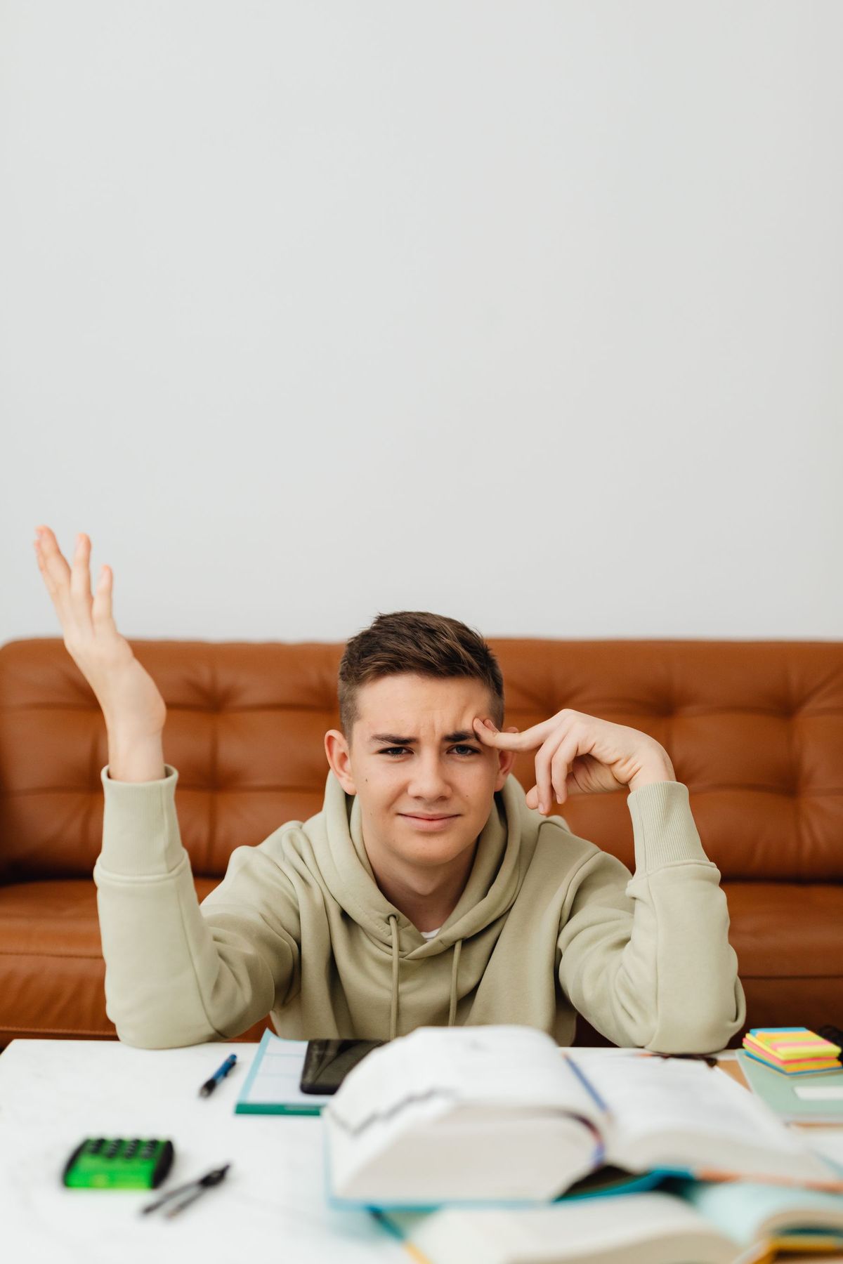 Man at a table raising his hand with a puzzled expression