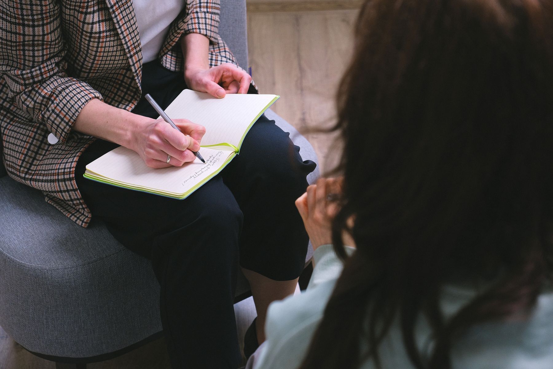 Counselor writing in a notebook while talking with a client