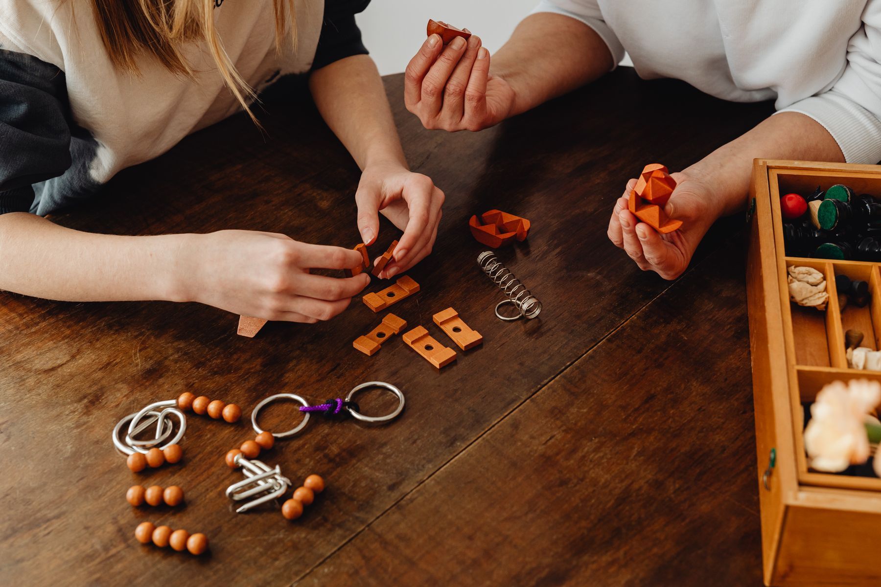 Adult and child hands working with small objects on a wooden table