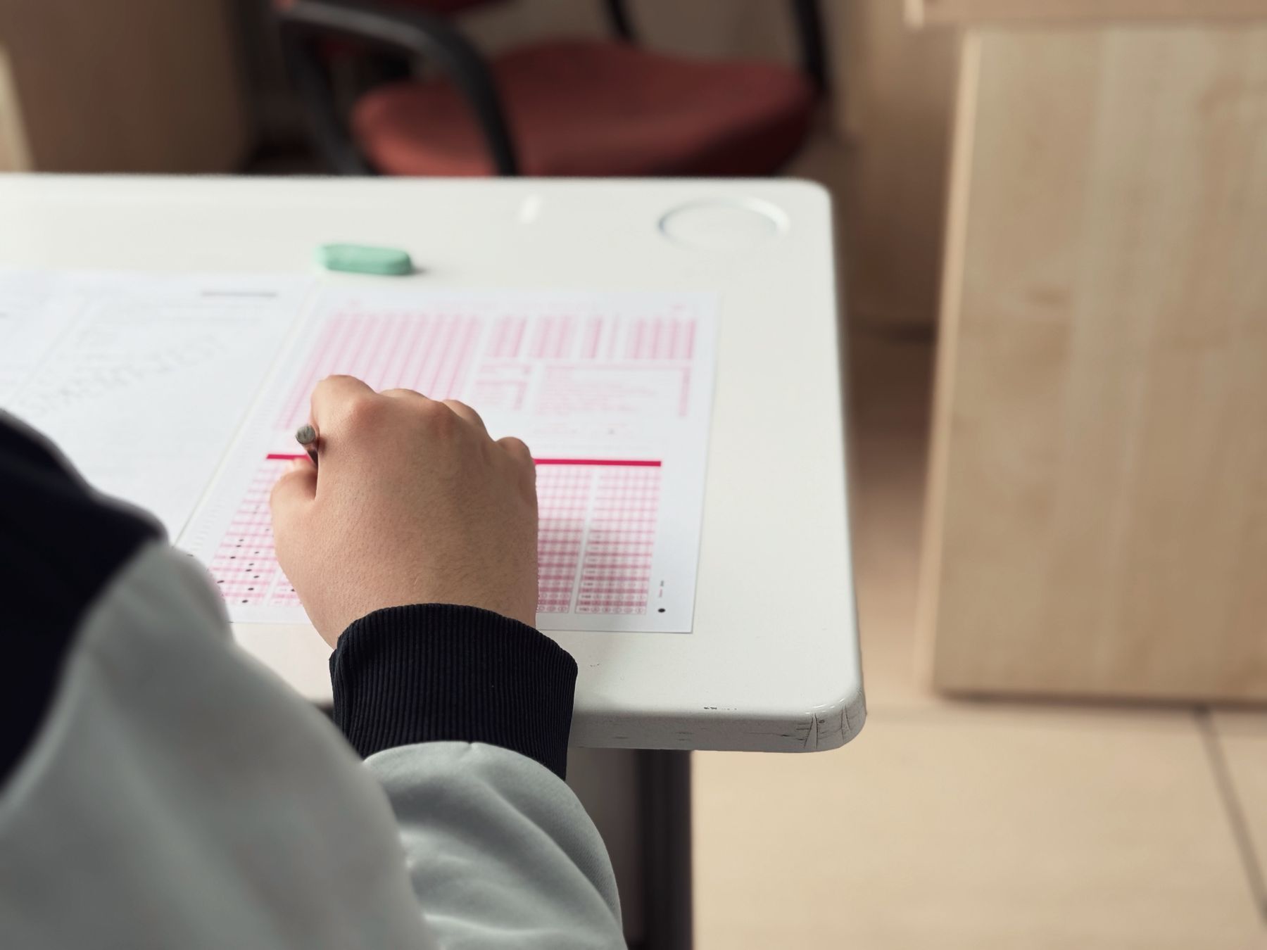 Student completing a written exam at a desk